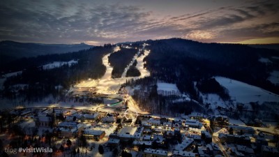 Stacja narciarska Skolnity z grupy Pingwina, a na pierwszym planie centrum Wisły o zachodzie słońca.